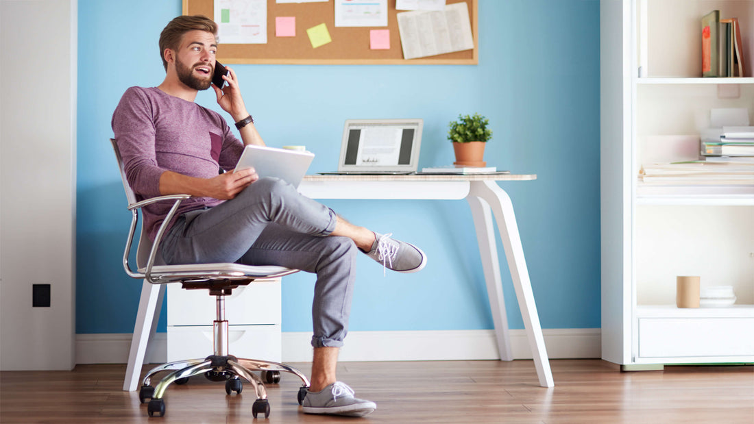 Man seated on a conventional office chair while working.